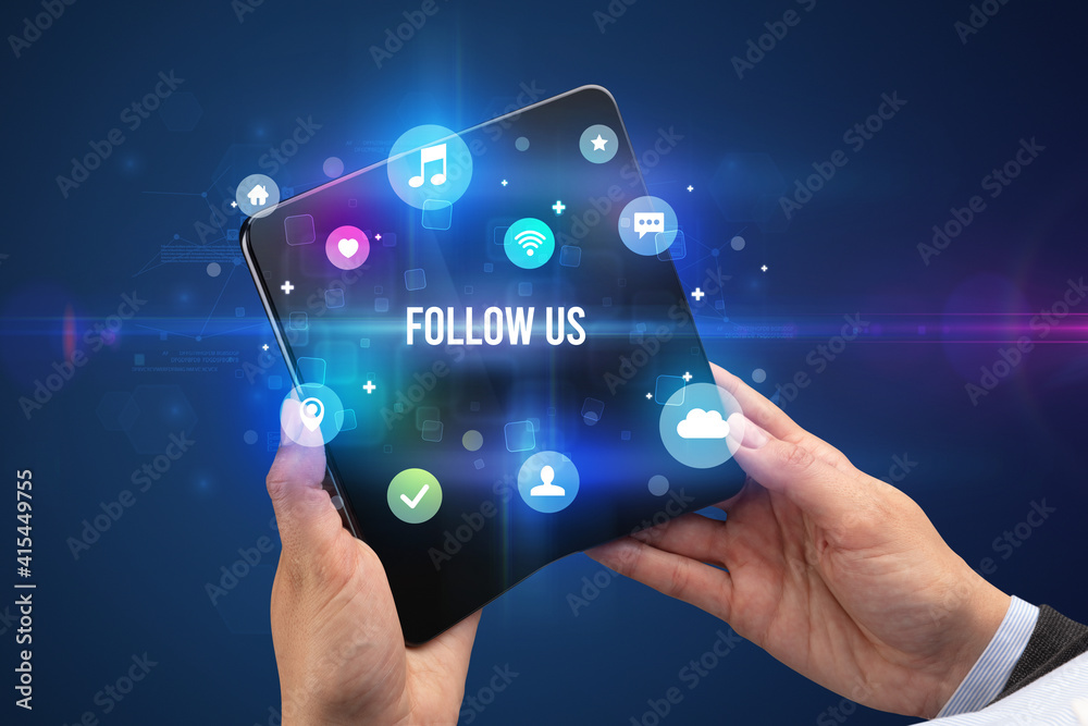 Businessman holding a foldable smartphone with FOLLOW US inscription, social media concept Businessman holding a foldable smartphone with FOLLOW US inscription, social media concept