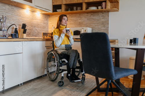 Woman sitting in her wheelchair and drinking coffee