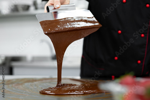 Close-up of a pastry chef using spatulas tempering molten chocolate
