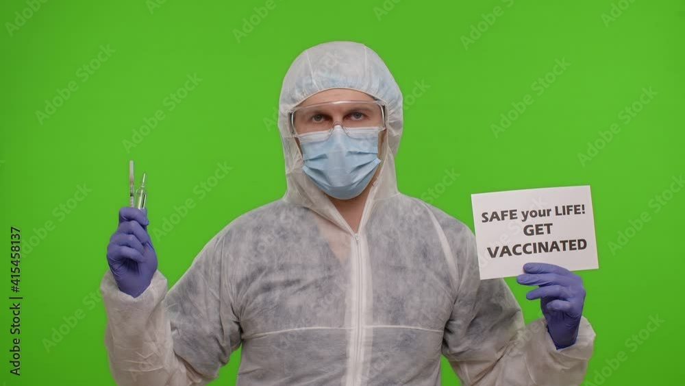 Medical worker doctor in PPE suit with syringe, ampoule and text slogan on paper - Safe Your Life Get Vaccinated. Isolated on chroma key offering vaccination injection against coronavirus pandemic Medical worker doctor in PPE suit with syringe, ampoule and text slogan on paper - Safe Your Life Get Vaccinated. Isolated on chroma key offering vaccination injection against coronavirus pandemic
