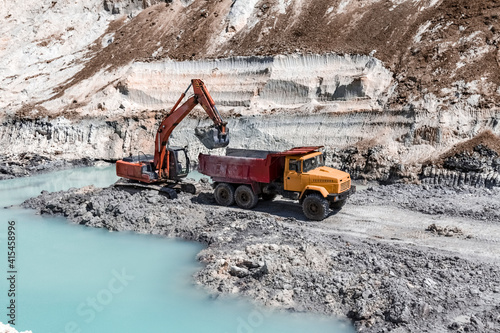 The excavator is extracting a watered layer of minerals in a clay quarry.