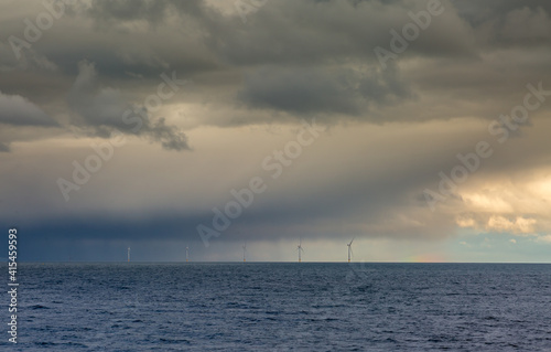Several windmills off the coast of Tynemouth in the northeast of England, on a cloudy with a faint rainbow in view