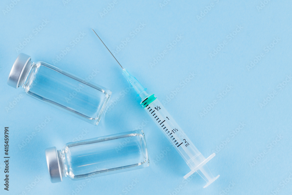 Vaccine and syringe injection. Vaccines and syringe on a blue background for prevention and immunization. Vaccine and healthcare medical concept. Copy space Vaccine and syringe injection. Vaccines and syringe on a blue background for prevention and immunization. Vaccine and healthcare medical concept. Copy space