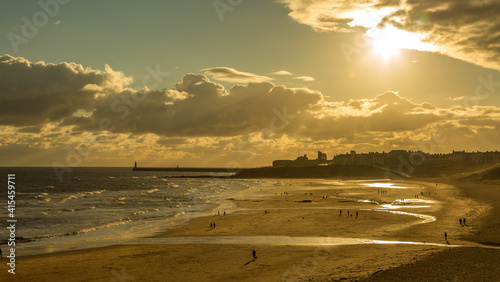 People taking a walk on Tynemouth's Longsands beach during Lockdown on a cloudy and rainy day, in the north east of England photo