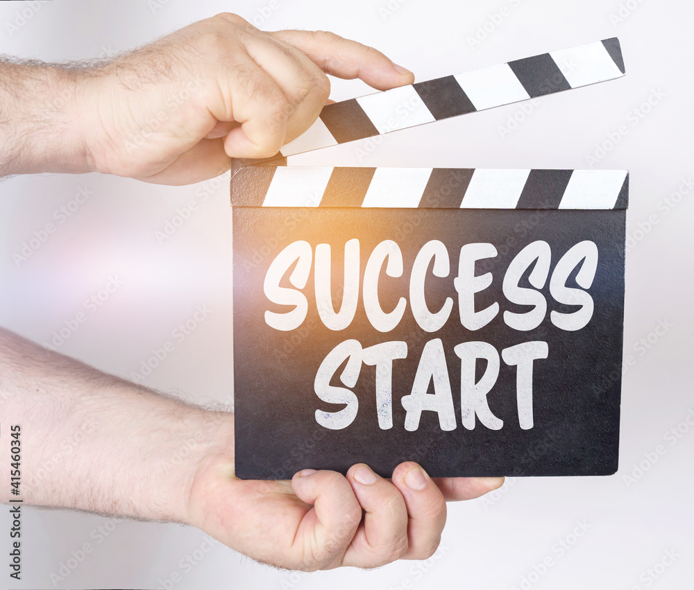 On a white background, a man holds a clapperboard in his hands on which it is written - SUCCESS START
