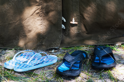 Obraz na płótnie Two pairs of women's and men's summer beach slippers near tourist tent in forest. Family trip, romance concept. Selective focus. w salonie