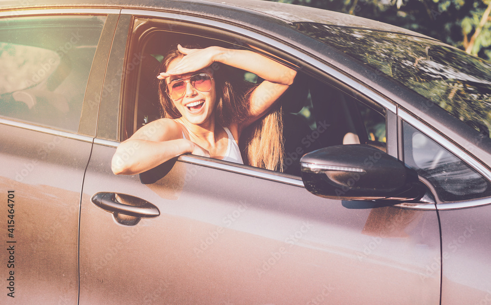 Naklejka premium Portrait of pretty smiling woman in car window. Concept traveler tourist trip by avtomobil.