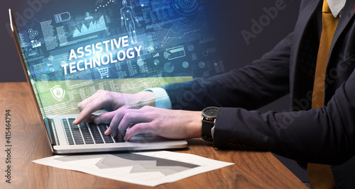 Businessman working on laptop with ASSISTIVE TECHNOLOGY inscription, cyber technology concept