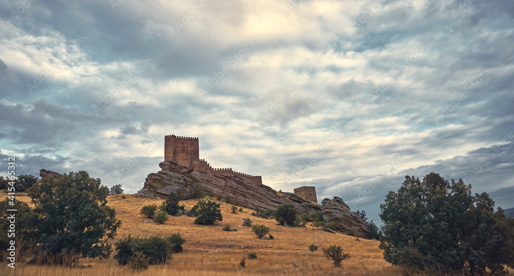 Natural landscape with a medieval castle on top of a hill and the sun's rays through the clouds. Zafra Castle
