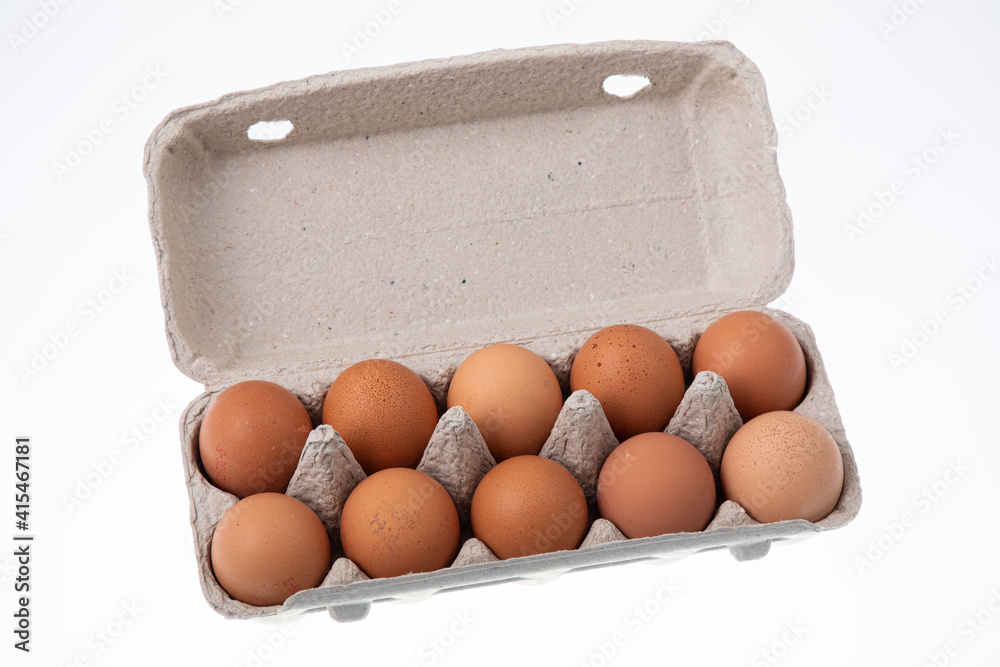 Top view of ten raw chicken eggs in egg box on white background