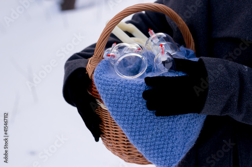 A woman in a gray coat holds a basket of hijama cans. Hijama jars and hijama pump, bloodletting, Chinese medicine