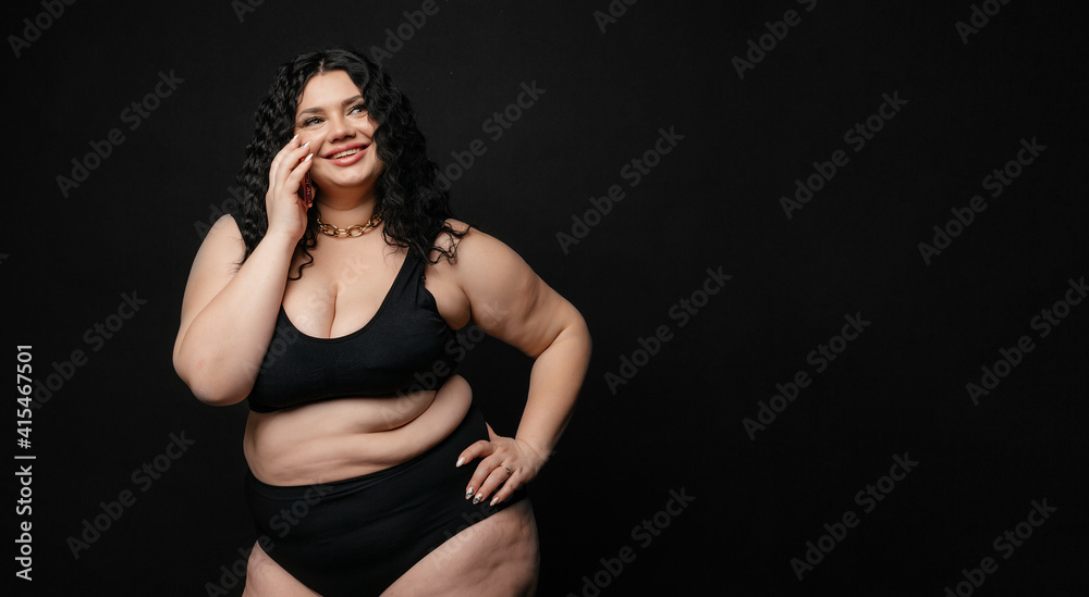 Plus size model in lingerie, fat sexy woman in underwear on black studio background, body positive concept, full length portrait. Girl model plus size talking on the phone