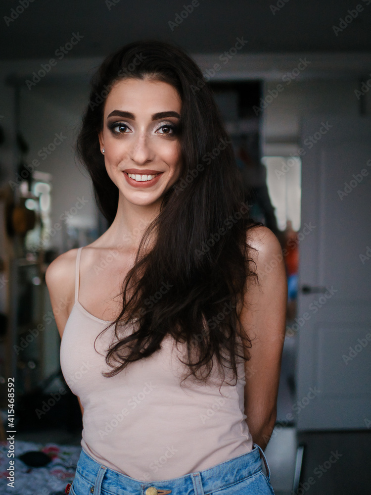 Lifestyle closeup natural light portrait of young pretty thoughtful brunette woman in shoulder straps blouse room domestic background Lifestyle closeup natural light portrait of young pretty thoughtful brunette woman in shoulder straps blouse room domestic background