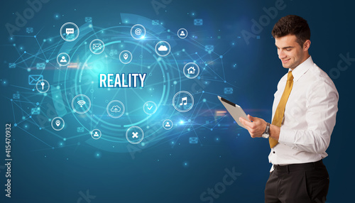 Businessman thinking in front of technology related icons and REALITY inscription, modern technology concept