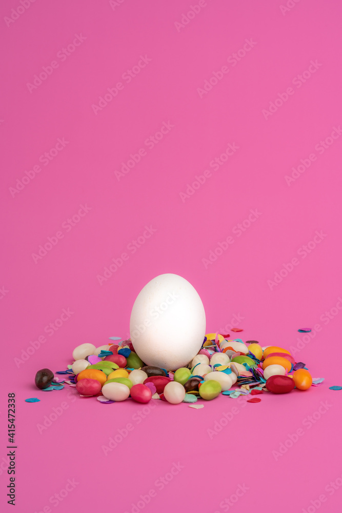 a card design with copy space for easter in pink.in the center a white Easter egg surrounded by sugared small colorful little Easter eggs a card design with copy space for easter in pink.in the center a white Easter egg surrounded by sugared small colorful little Easter eggs