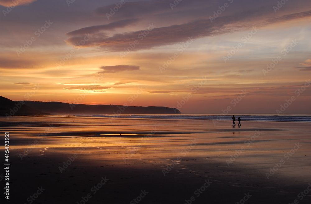 Couple walking on beach at Sunset, Whitby