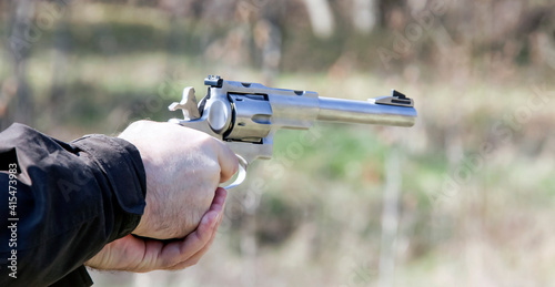 Silver pistol in the hands of the shooter before the shot.