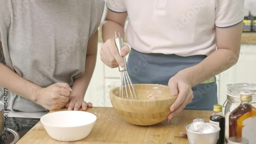 Mom is teaching her son to mix flour to make cookies. At home happily