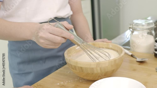 Asian boy hands putting mix of yolks with smile face , starch, sugar and milk in milk for making custard cream at home.