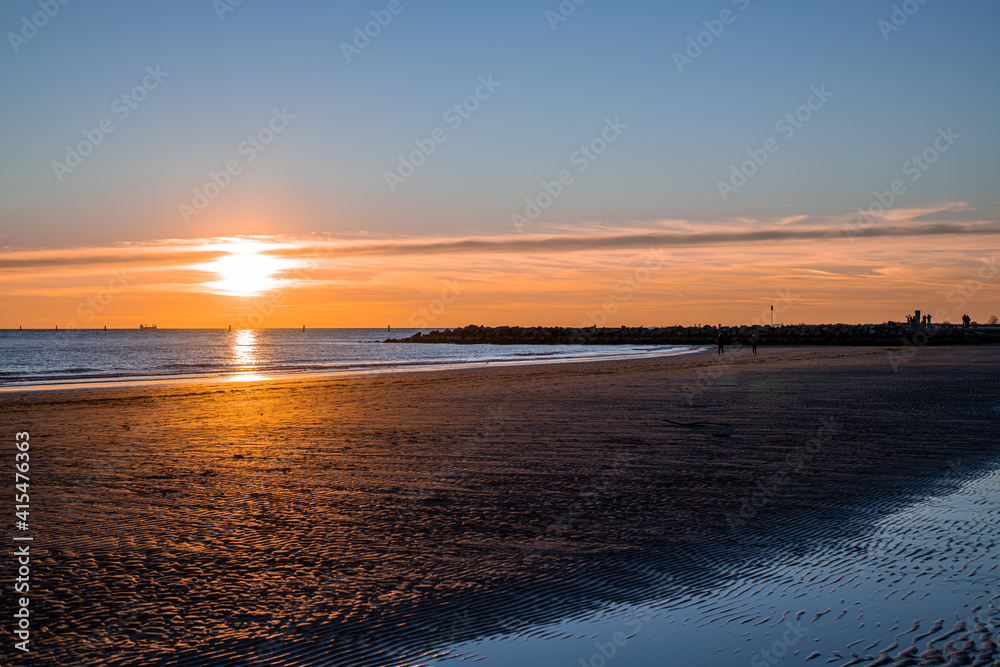 sunset at sea, sun on the same level with the sea and casual passers-by on the run sunset at sea, sun on the same level with the sea and casual passers-by on the run