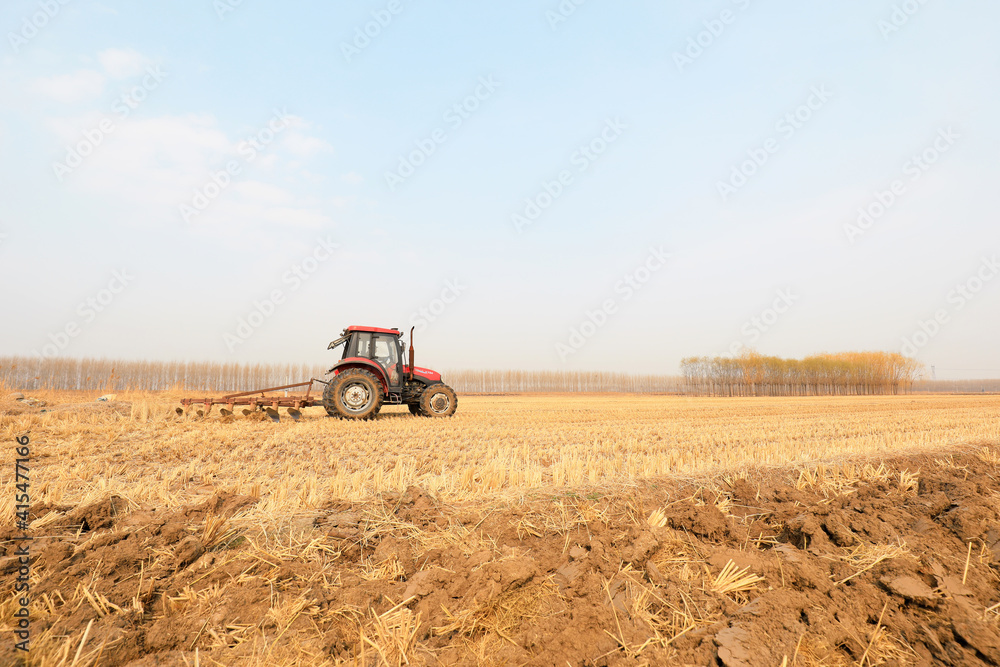 Obraz premium Farmers drive tractors to plow land in farmland, North China