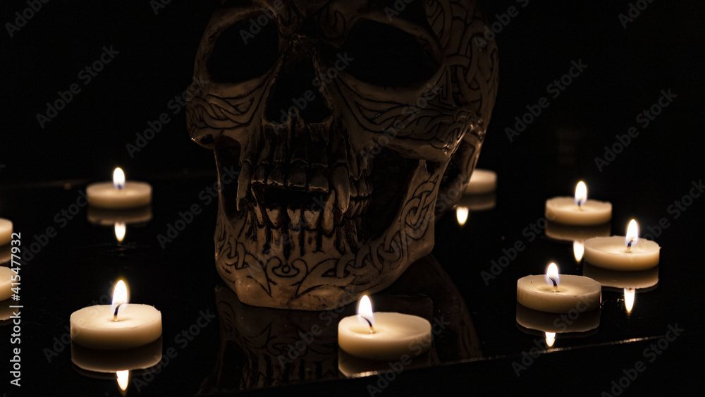Teschio illuminato da candele con sfondo nero Teschio illuminato da candele con sfondo nero