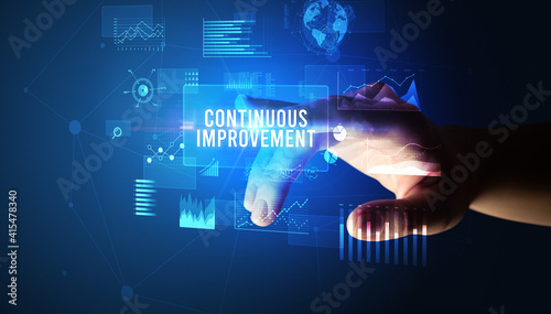 Hand touching CONTINUOUS IMPROVEMENT inscription, new business technology concept