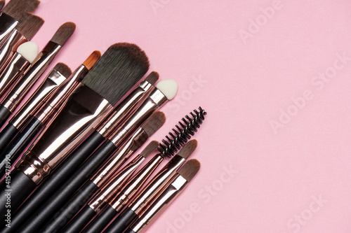 Fototapeta Naklejka Na Ścianę i Meble -  Make up brush sets arranged on pink background, top view with copy space. Cosmetics products.