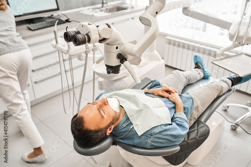 Dentist looking at the patient using binocular microscope