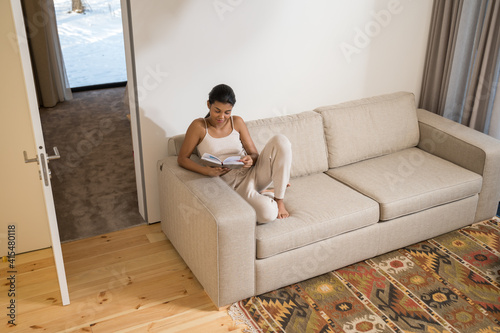 Woman sitting on couch distracted from reading a book