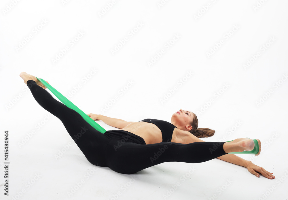 Sport, yoga and fitness concept: Young woman exercising doing workout for legs with elastic bands lying on floor isolated on white background