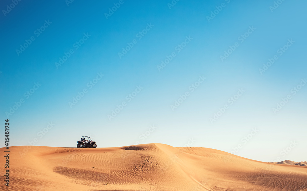 Minimalistic desert view with blue sky, sand hill and one buggy quad bike, motor sport adventures, driving off-road Minimalistic desert view with blue sky, sand hill and one buggy quad bike, motor sport adventures, driving off-road