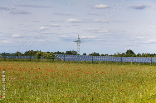 renewable energy, landscape and solar panels, field with wild poppies on a summer day with solar panels