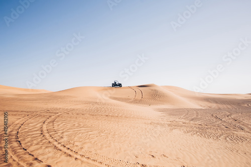 Beautiful desert landscape with wheel traces and black buggy quad bike up on hill, Al awir sand dunes, Dubai, UAE  