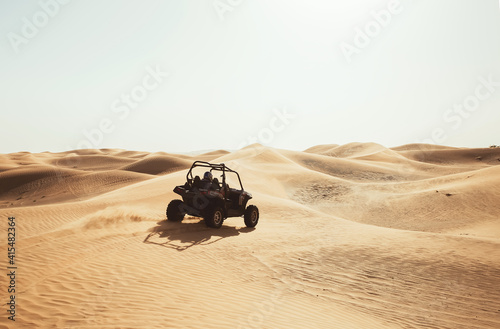 Silhouette of buggy quad bike in desert sand dunes during safari tour, extreme driving fun adventures during sunny day