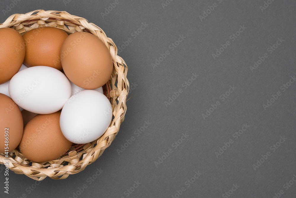 White and brown eggs in the basket on a gray table. Easter. Top view White and brown eggs in the basket on a gray table. Easter. Top view