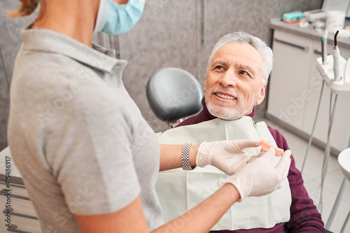 Doctor holding dentures or artificial teeth for man