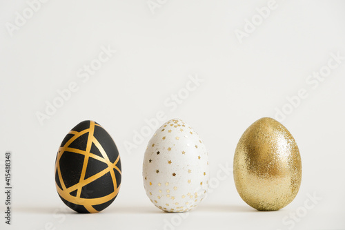 Wall Mural Three Easter golden decorated eggs isolated on white background