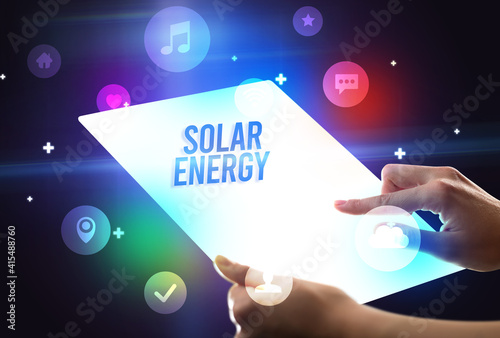 Holding futuristic tablet with SOLAR ENERGY inscription, new technology concept