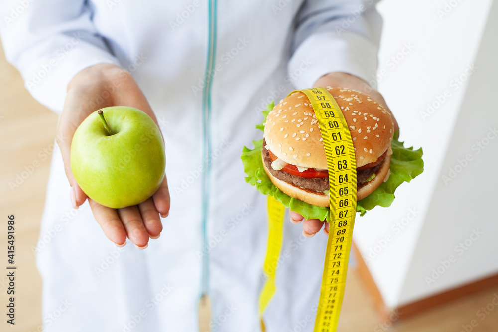 Diet concept, woman holding a choice of harmful hamburger and fresh apple Diet concept, woman holding a choice of harmful hamburger and fresh apple