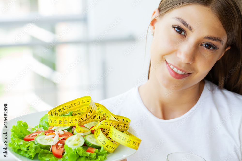 Young woman hold healthy salad with green fresh ingredients and yellow tape Young woman hold healthy salad with green fresh ingredients and yellow tape