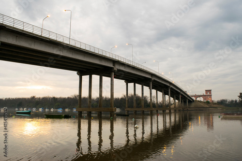 Sol naciente reflajado en el rio, debajo de un puente © migueq86