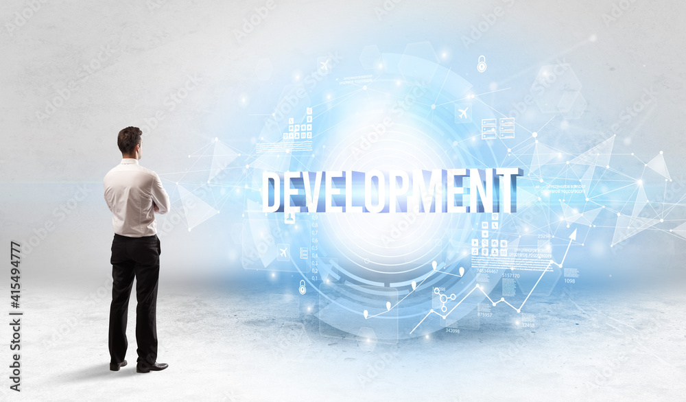 Rear view of a businessman standing in front of DEVELOPMENT inscription, modern technology concept Rear view of a businessman standing in front of DEVELOPMENT inscription, modern technology concept