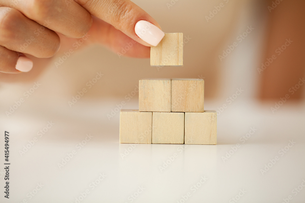 Hand putting and stacking blank wooden cubes on table with copy space for input wording and infographic icon. Hand putting and stacking blank wooden cubes on table with copy space for input wording and infographic icon.