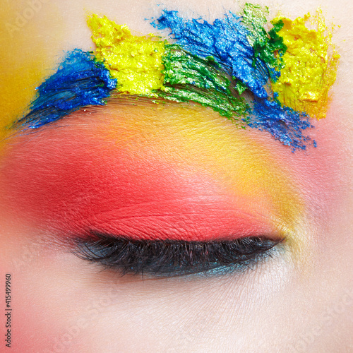 Close-up macro shot of closed teenager female eye with unusual art make-up and face painting on brows and around eye.