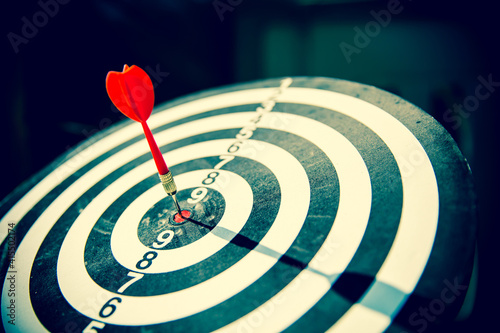 Close-up the bullseye target or or dart board has dart arrow throw hitting the center of a shooting for business targeting and aim to winning goals concepts