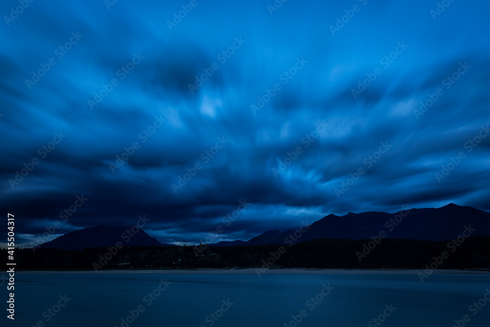 Long exposure blue hour landscape with a looming cloudy sky, Lake Koocanusa on the foreground and mountains on the background, British Columbia, Canada