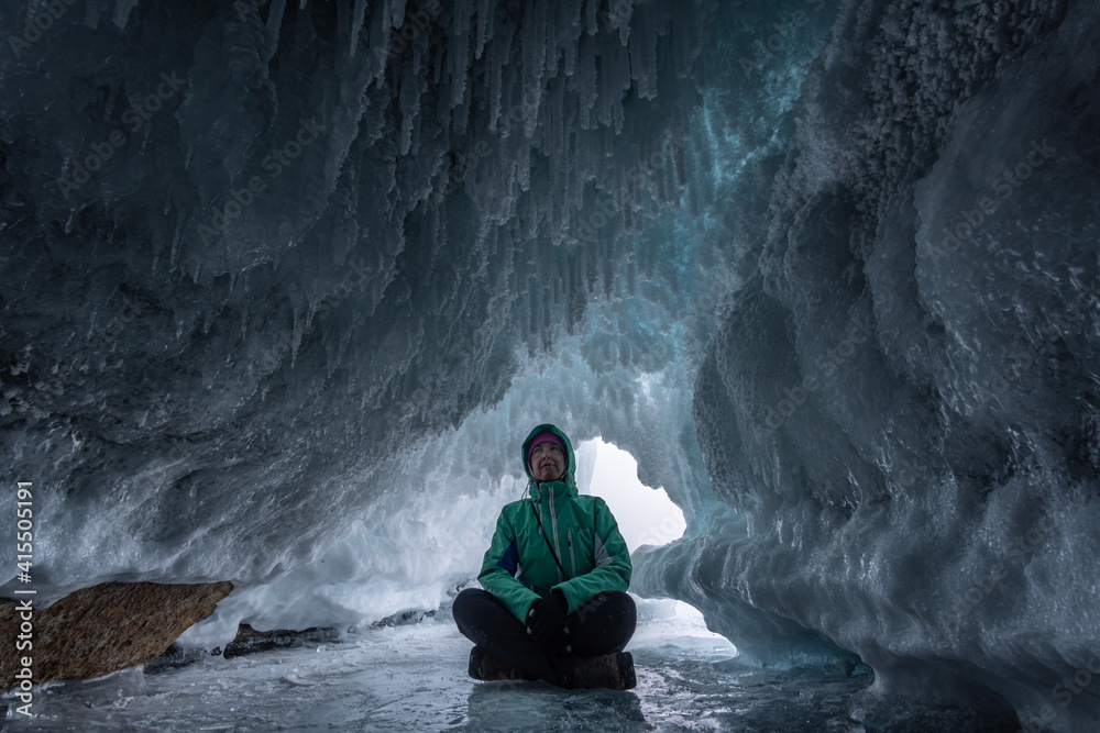Fototapeta premium A tourist sits in an ice grotto on Lake Baikal