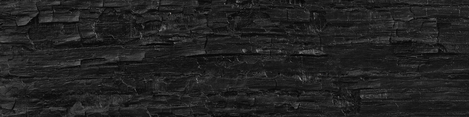 Dark black background of rough burnt wood, soot, and ash. Burn texture.