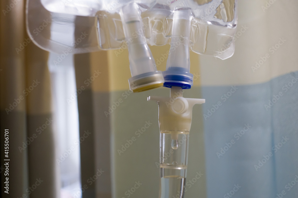 Bag of intravenous fluid drips. infuses saline and other injected drugs into patient in hospital room. Bag of intravenous fluid drips. infuses saline and other injected drugs into patient in hospital room.